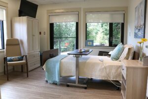A bed in a comfortable bedroom with windows looking out to a wooded area.